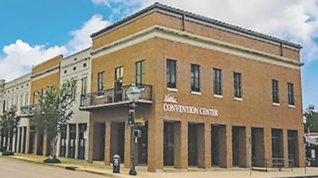 Light tan brick building on the corner of a downtown street with Convention Center sign